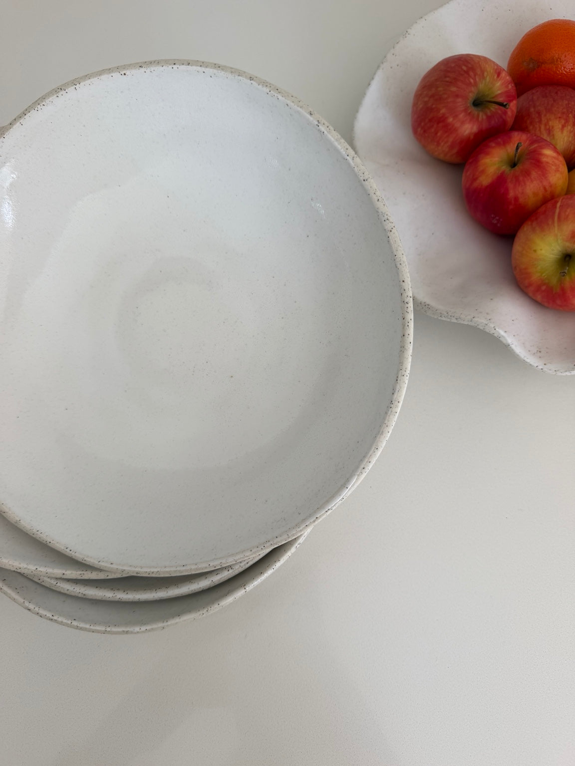 Stacked Petra Bowls beside a handmade fruit platter with apples